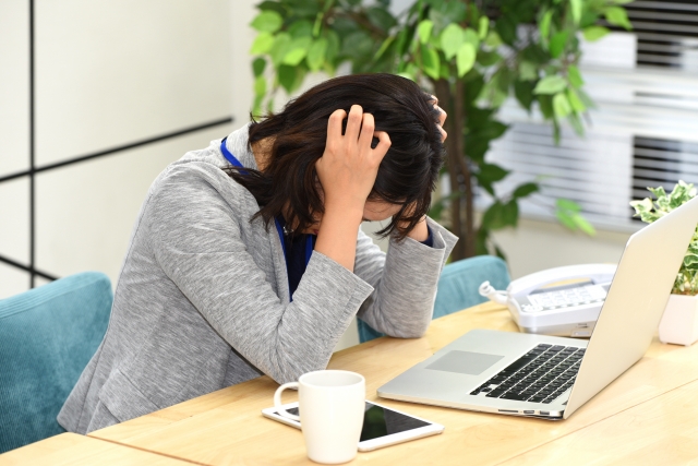 頭を抱え悩み事をする女性